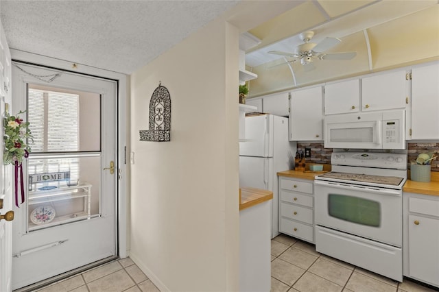 kitchen with light tile patterned floors, white appliances, a textured ceiling, and white cabinets