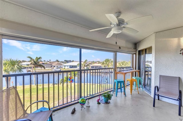 sunroom / solarium featuring lofted ceiling, ceiling fan, and a water view