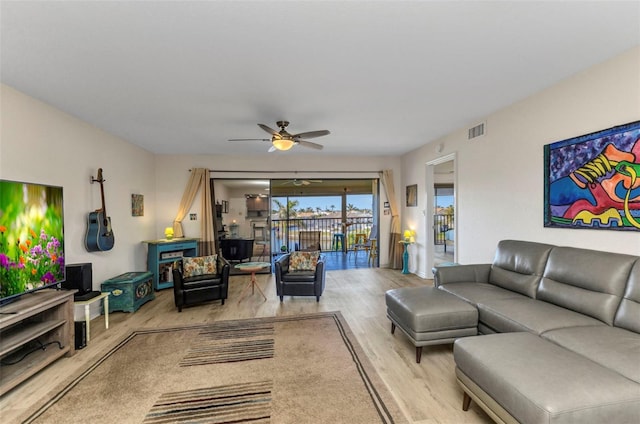 living area featuring visible vents, wood finished floors, and a ceiling fan