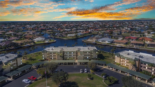 aerial view at dusk with a water view and a residential view