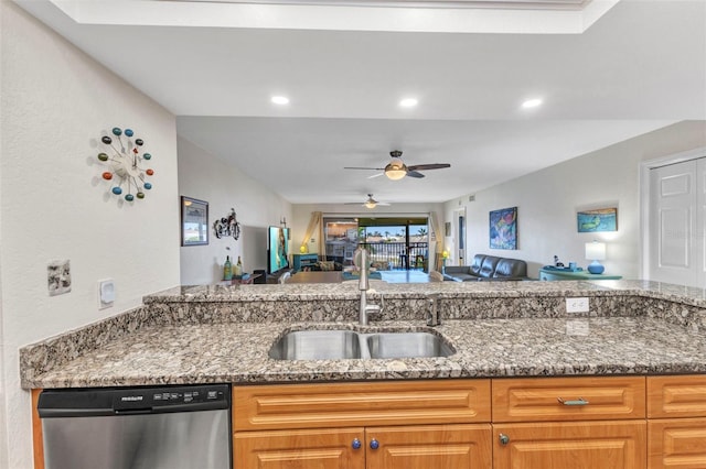 kitchen featuring open floor plan, dishwasher, stone countertops, and a sink