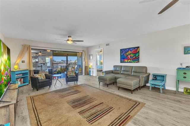 living area featuring baseboards, wood finished floors, visible vents, and ceiling fan