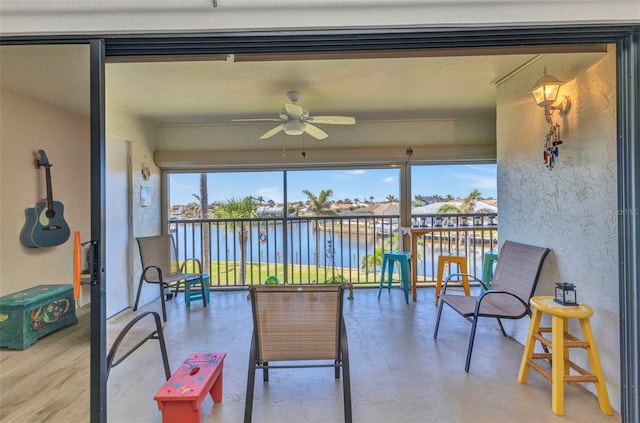 sunroom featuring a water view and a ceiling fan