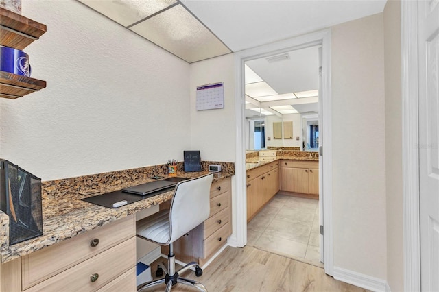 office space with built in desk and light wood-type flooring