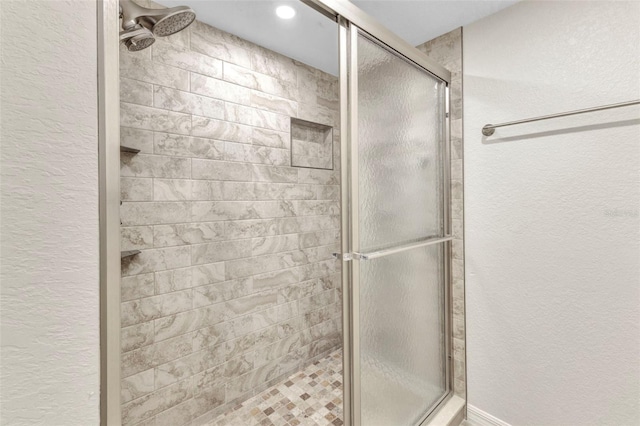 bathroom featuring a shower stall and a textured wall