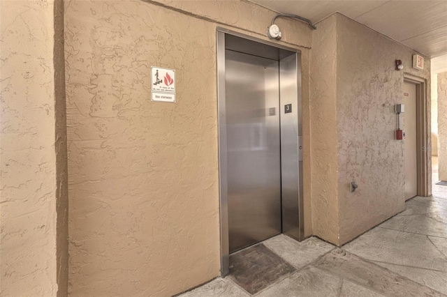 bathroom featuring elevator and a textured wall