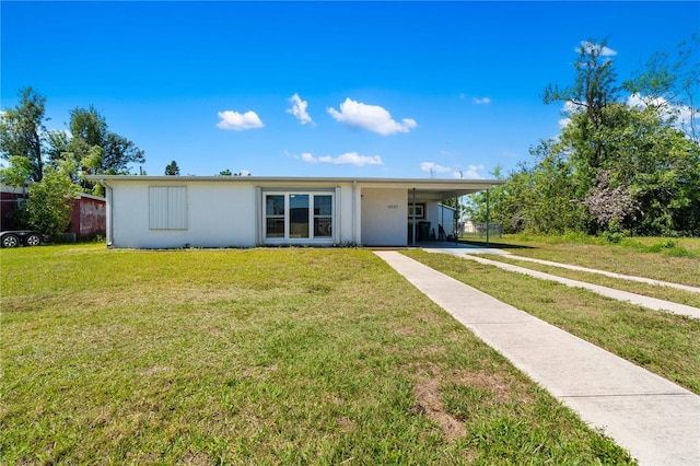 ranch-style home featuring stucco siding, driveway, a carport, and a front yard