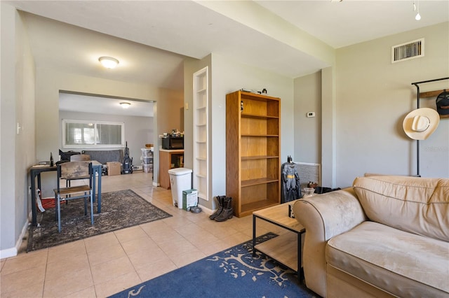 living area with built in features, visible vents, baseboards, and tile patterned flooring