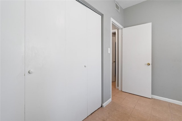 unfurnished bedroom featuring a closet, visible vents, baseboards, and light tile patterned flooring