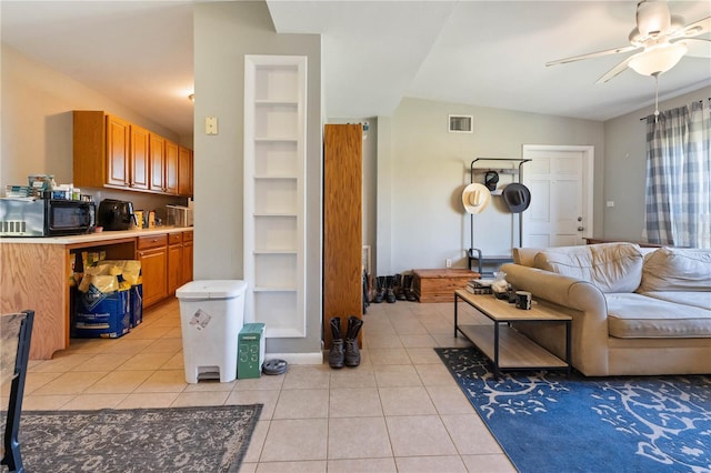 living area with light tile patterned floors, visible vents, built in shelves, and ceiling fan