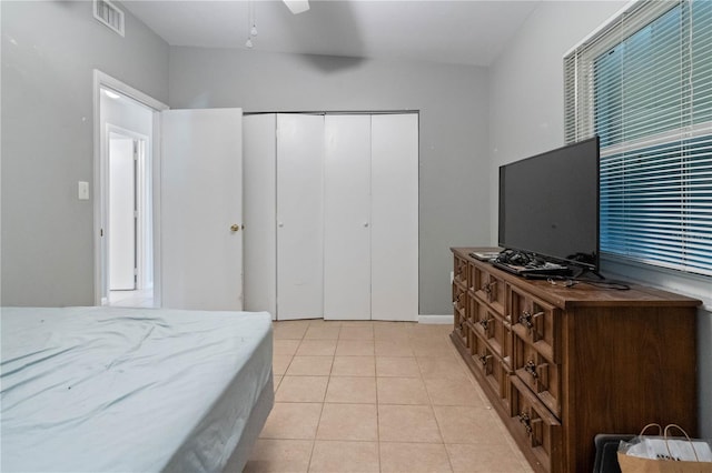 bedroom featuring light tile patterned floors, visible vents, a closet, and ceiling fan