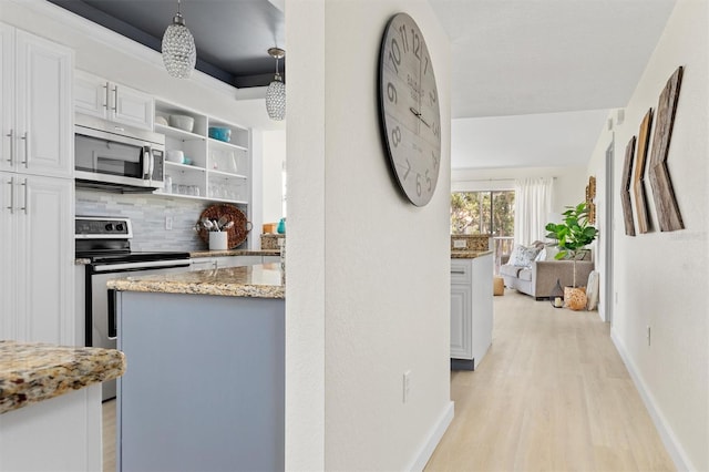 kitchen with open shelves, tasteful backsplash, appliances with stainless steel finishes, light wood finished floors, and light stone countertops