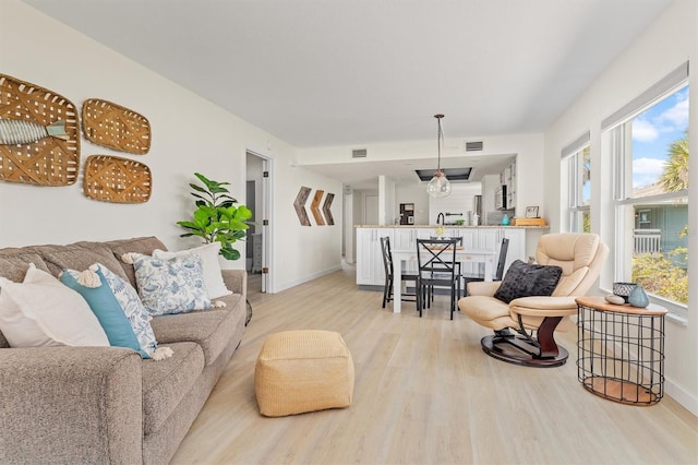 living area with visible vents, light wood-style floors, and a healthy amount of sunlight