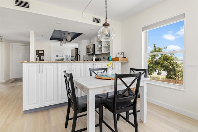 dining area with visible vents, baseboards, and light wood-style flooring