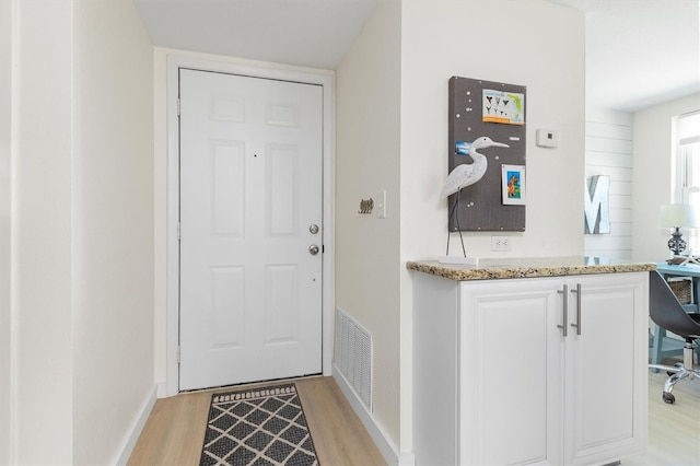 doorway featuring baseboards, visible vents, and light wood-type flooring