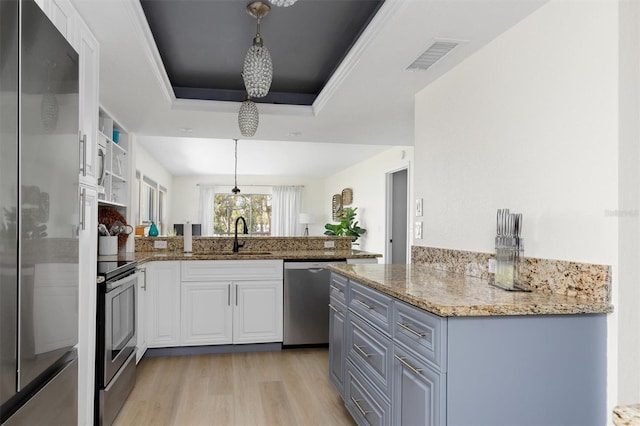 kitchen featuring visible vents, a peninsula, a tray ceiling, appliances with stainless steel finishes, and white cabinetry