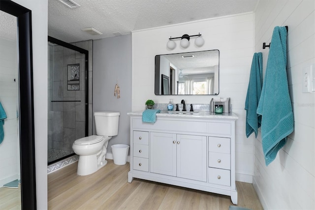 full bath with a shower stall, toilet, wood finished floors, and a textured ceiling