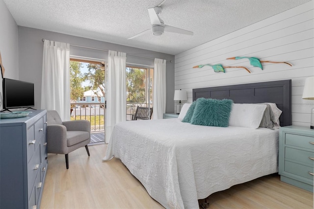 bedroom featuring access to exterior, light wood-style flooring, a ceiling fan, and a textured ceiling