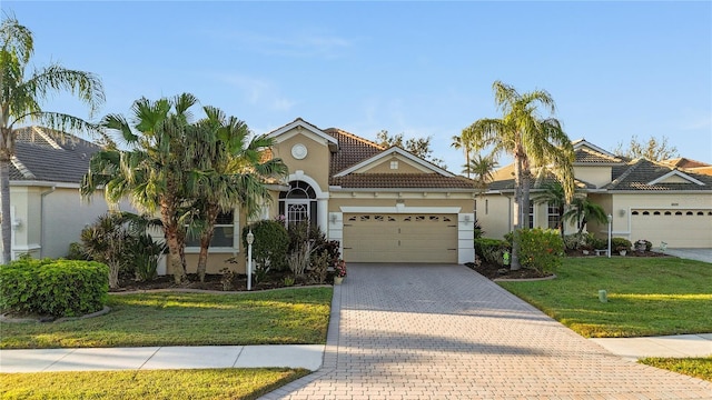 view of front of home featuring an attached garage, a tiled roof, a front yard, stucco siding, and driveway