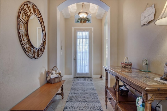 foyer featuring arched walkways, light tile patterned floors, and baseboards