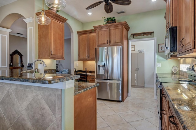 kitchen with visible vents, brown cabinets, arched walkways, stainless steel appliances, and a ceiling fan