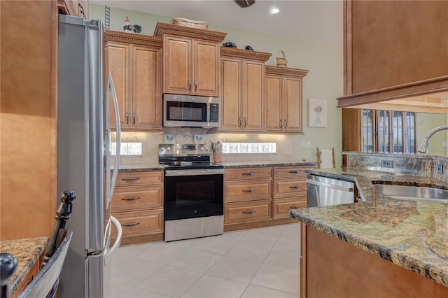 kitchen featuring decorative backsplash, dark stone countertops, appliances with stainless steel finishes, and a sink