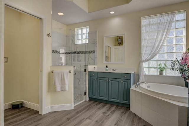 full bathroom featuring a shower stall, vanity, a garden tub, and wood finished floors