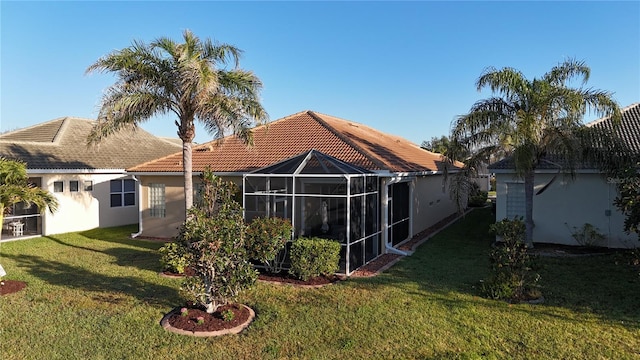 rear view of property with glass enclosure, a yard, stucco siding, and a tile roof