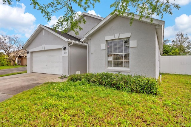 view of front of house featuring a front lawn, fence, concrete driveway, stucco siding, and a garage