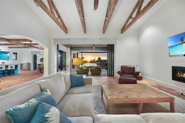 1111 San Mateo Dr, Punta Gorda, FL 33950 - tiled living area featuring beamed ceiling, a ceiling fan, a glass covered fireplace, arched walkways, and baseboards