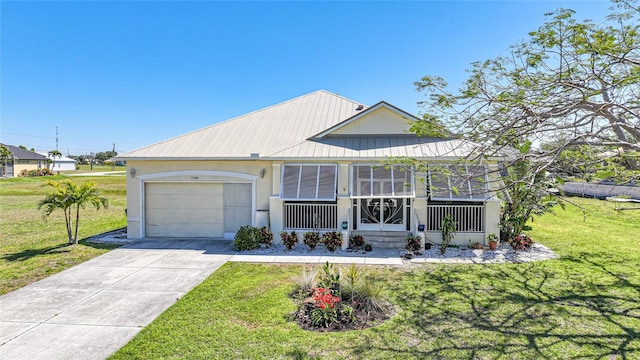 view of front of property with a front yard, driveway, an attached garage, stucco siding, and metal roof