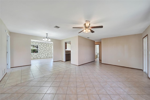 spare room with light tile patterned floors, ceiling fan with notable chandelier, visible vents, and baseboards