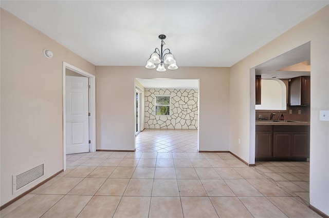 unfurnished dining area with visible vents, baseboards, light tile patterned floors, a notable chandelier, and a sink