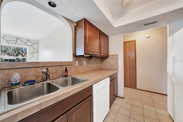 kitchen featuring white appliances, visible vents, a sink, decorative backsplash, and light countertops