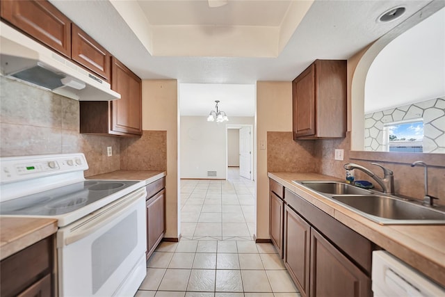 kitchen featuring baseboards, under cabinet range hood, light countertops, white appliances, and a sink