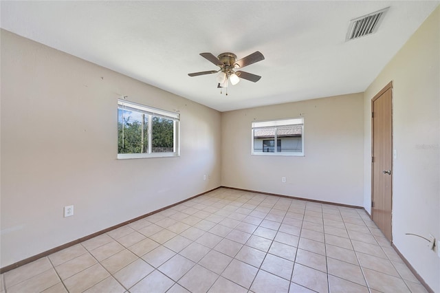 spare room featuring light tile patterned floors, baseboards, visible vents, and ceiling fan