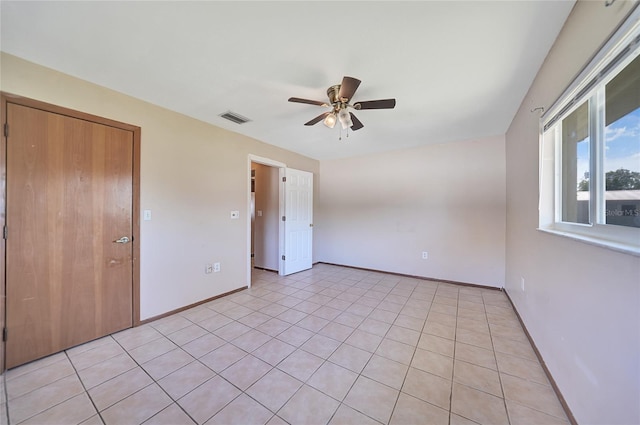 empty room featuring visible vents, baseboards, light tile patterned flooring, and a ceiling fan