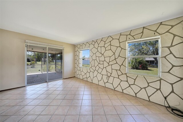 empty room with an accent wall and light tile patterned floors