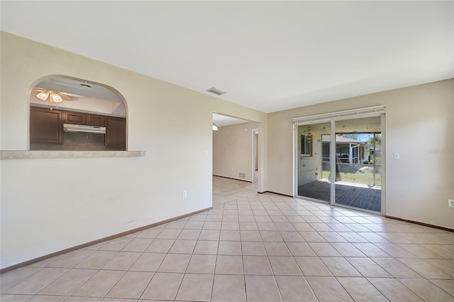 empty room featuring visible vents, baseboards, arched walkways, and light tile patterned flooring