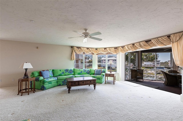 living area with a textured ceiling, carpet floors, and ceiling fan