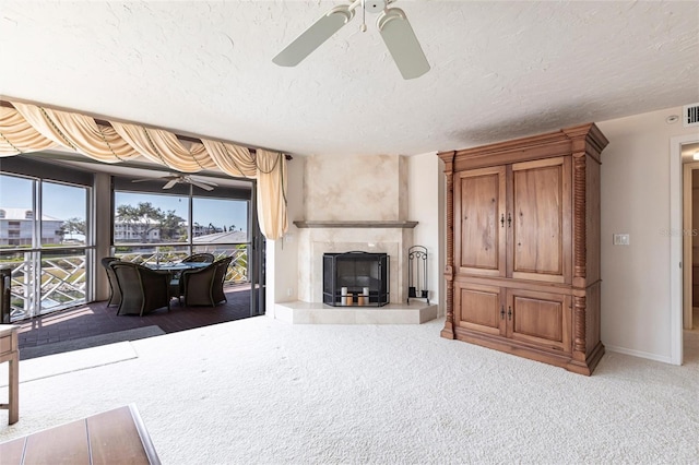 unfurnished living room featuring a ceiling fan, a textured ceiling, carpet floors, baseboards, and a tile fireplace