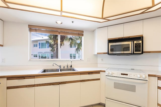 kitchen featuring stainless steel microwave, electric range, light countertops, and a sink