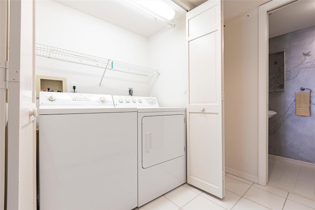 laundry room featuring light tile patterned floors, baseboards, separate washer and dryer, and laundry area