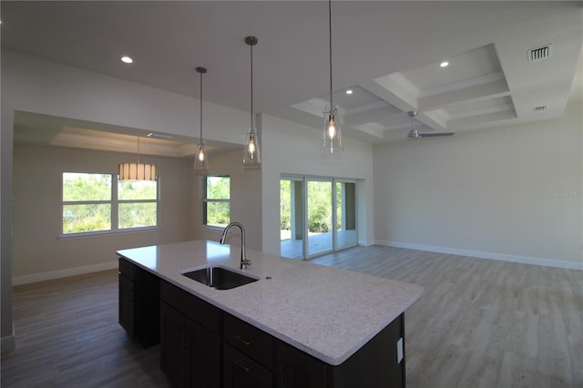 kitchen featuring visible vents, baseboards, open floor plan, light wood-style flooring, and a sink