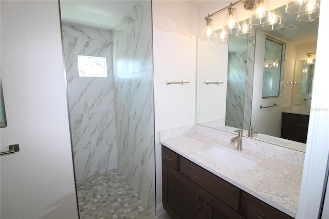 full bath featuring a marble finish shower, visible vents, and vanity