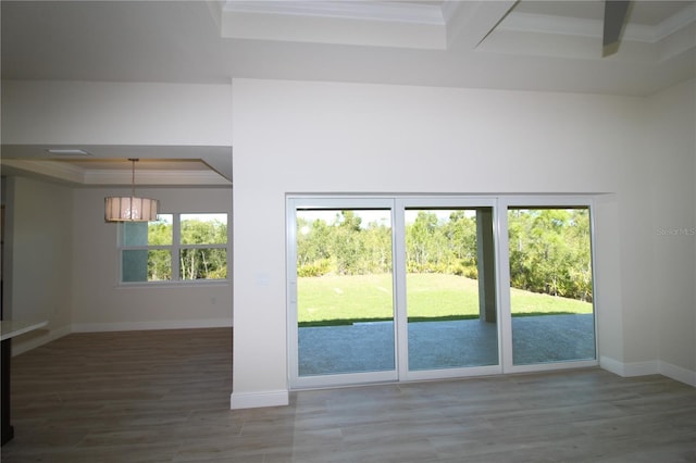 doorway featuring crown molding, baseboards, beamed ceiling, a tray ceiling, and wood finished floors