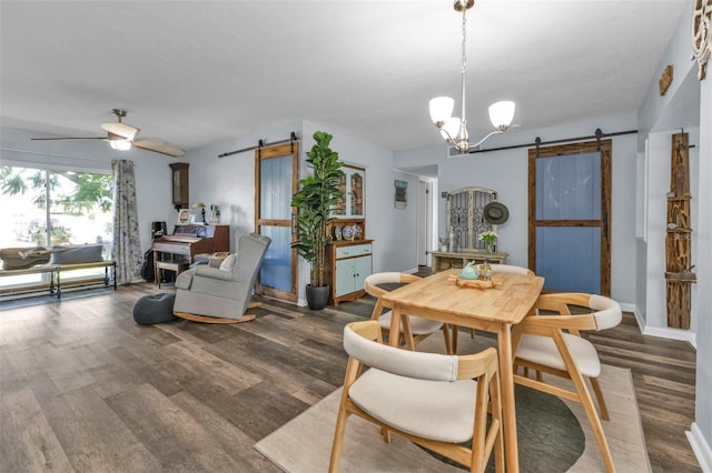 dining area with ceiling fan with notable chandelier, a barn door, and wood finished floors