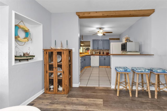 kitchen with light wood finished floors, backsplash, white appliances, a ceiling fan, and a sink