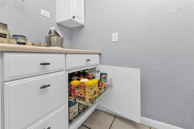 details featuring white cabinetry, light countertops, and a textured wall