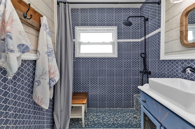 full bathroom with tiled shower, tile walls, and vanity